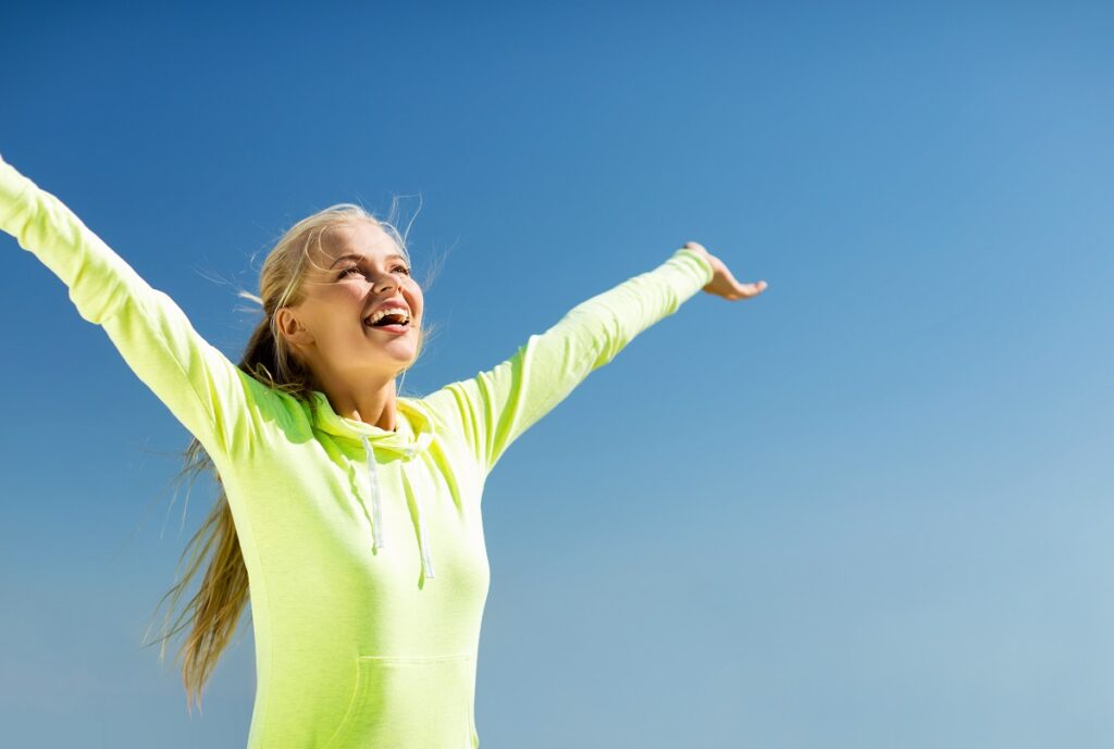 Smiling woman with her arms up enjoying the sun